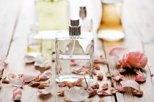 A perfume bottle on a wood table surrounded by rose petals